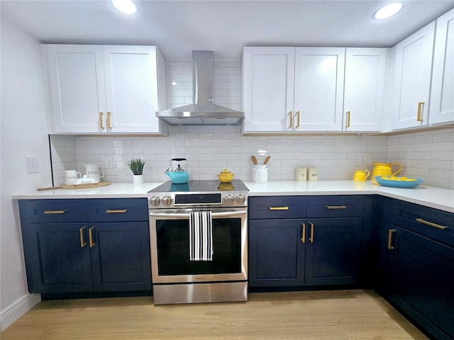 kitchen with stainless steel range with electric stovetop, white cabinetry, light wood-style floors, and wall chimney range hood