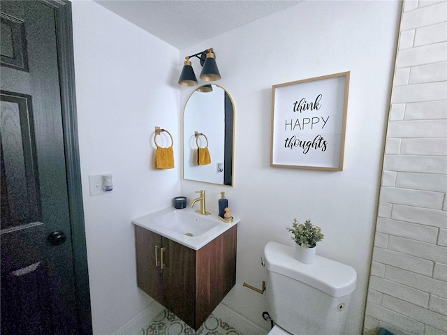 bathroom featuring toilet, vanity, and baseboards