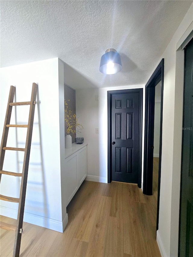 entryway with a textured ceiling, baseboards, and wood finished floors