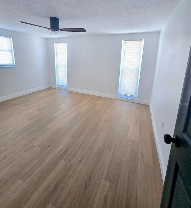 unfurnished room featuring baseboards, light wood-style floors, a ceiling fan, and a textured ceiling