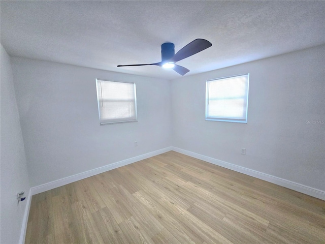 unfurnished room featuring plenty of natural light, light wood-style floors, baseboards, and a textured ceiling