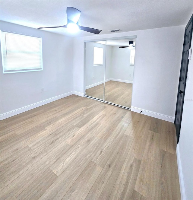 unfurnished bedroom with visible vents, ceiling fan, baseboards, and wood finished floors