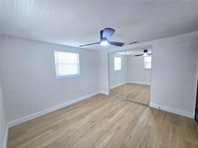 unfurnished bedroom featuring visible vents, light wood-style flooring, baseboards, and multiple windows