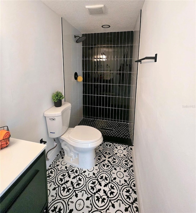 full bath with vanity, visible vents, a tile shower, tile patterned floors, and toilet