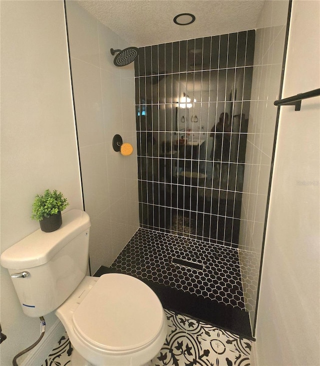 full bath featuring tile patterned floors, toilet, a shower stall, and a textured ceiling