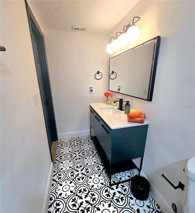 bathroom featuring visible vents, baseboards, vanity, tile patterned floors, and a textured ceiling