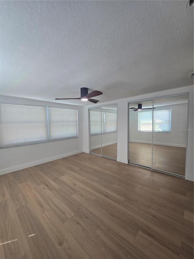 unfurnished bedroom with baseboards, multiple closets, and wood finished floors