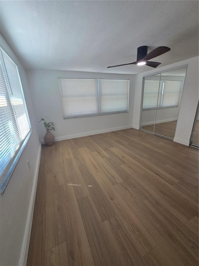 interior space with baseboards, a textured ceiling, wood finished floors, and a ceiling fan