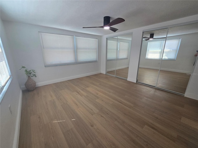 unfurnished bedroom featuring wood finished floors, multiple closets, and baseboards