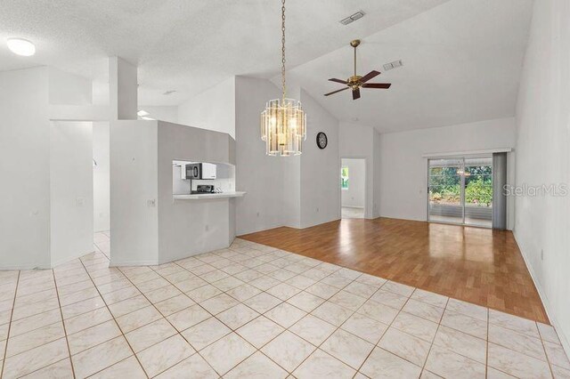 interior space with visible vents, light tile patterned flooring, and ceiling fan with notable chandelier