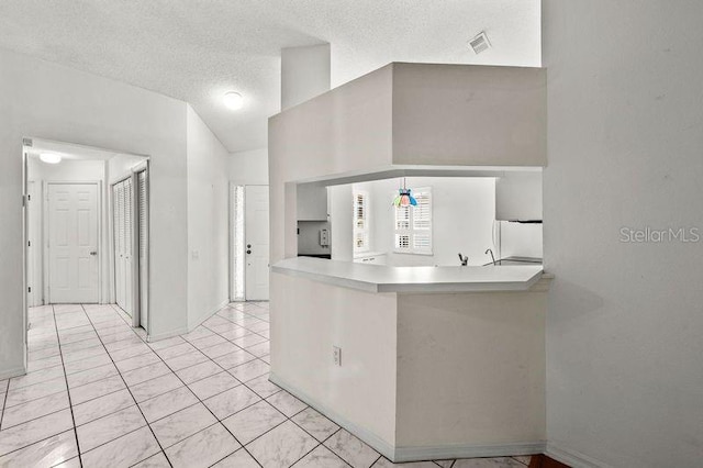 kitchen featuring visible vents, light tile patterned flooring, freestanding refrigerator, light countertops, and a textured ceiling