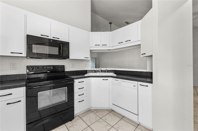 kitchen with dark countertops, white cabinetry, black appliances, and a sink