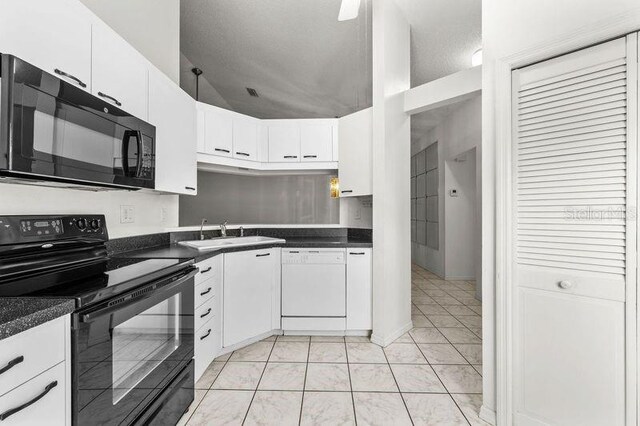 kitchen featuring dark countertops, white cabinetry, black appliances, and a sink