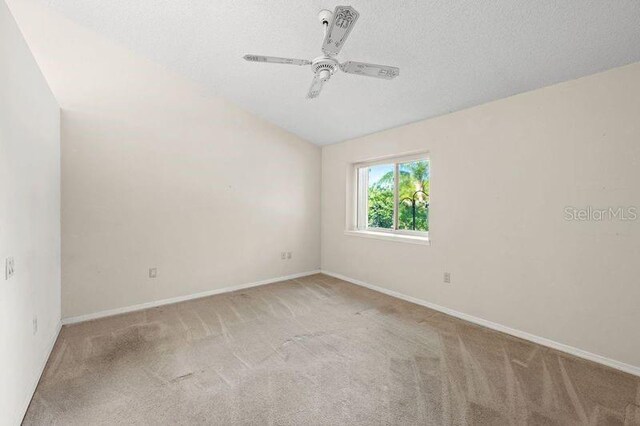 carpeted spare room with baseboards, lofted ceiling, a textured ceiling, and ceiling fan