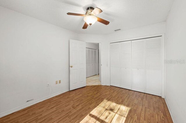 unfurnished bedroom featuring a textured ceiling, wood finished floors, a closet, and baseboards