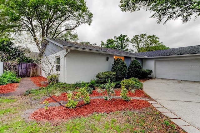 ranch-style house with stucco siding, an attached garage, driveway, and fence