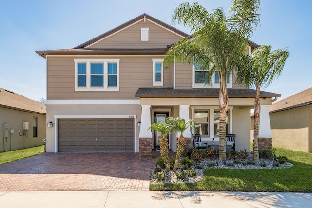 view of front of property featuring a garage, a porch, decorative driveway, and stone siding