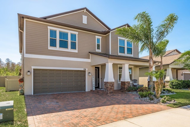 craftsman inspired home featuring decorative driveway, a garage, and stucco siding