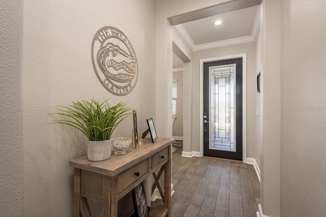 foyer entrance featuring dark wood-style floors, baseboards, ornamental molding, and a textured wall