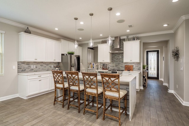 kitchen with visible vents, a center island with sink, stainless steel appliances, light countertops, and wall chimney exhaust hood