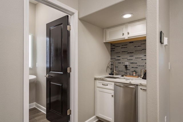 kitchen featuring a sink, baseboards, backsplash, and white cabinetry