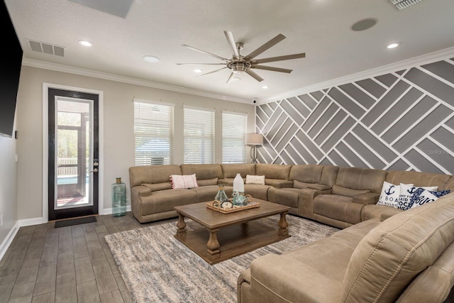 living area featuring visible vents, ornamental molding, wood finished floors, baseboards, and an accent wall