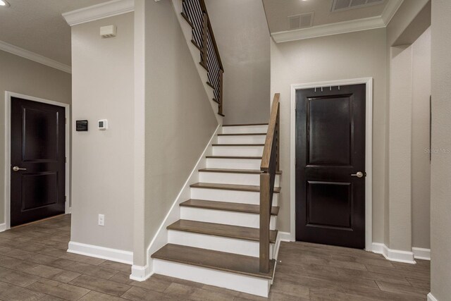 staircase featuring crown molding, baseboards, visible vents, and wood tiled floor