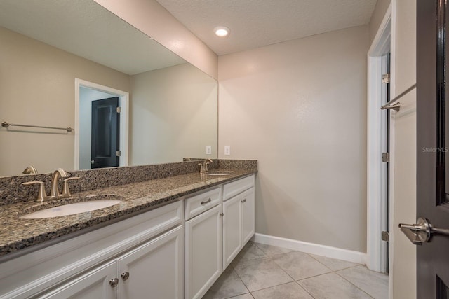 bathroom featuring a sink, baseboards, double vanity, and tile patterned flooring