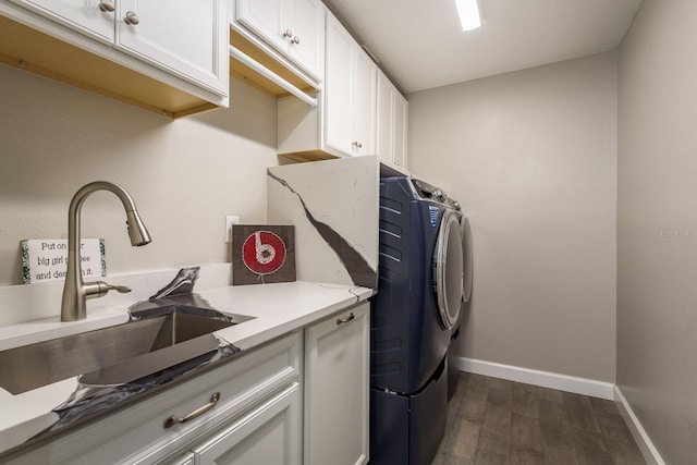 clothes washing area featuring baseboards, cabinet space, a sink, dark wood-type flooring, and independent washer and dryer