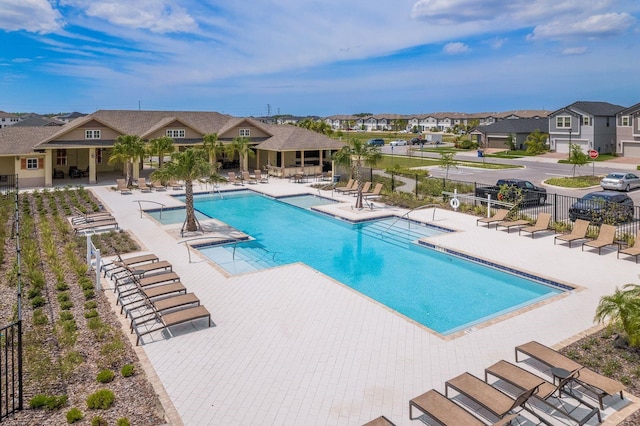 community pool featuring a patio area, a residential view, and fence