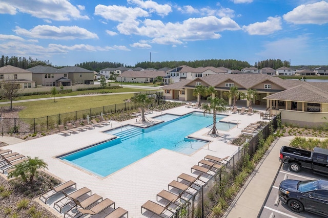 community pool with fence, a patio area, and a residential view