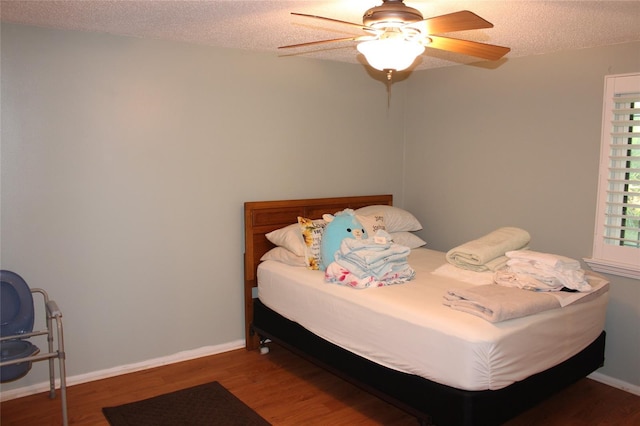 bedroom featuring ceiling fan, wood finished floors, baseboards, and a textured ceiling