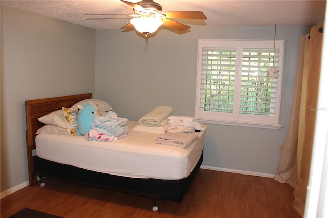 bedroom featuring ceiling fan, baseboards, a textured ceiling, and wood finished floors