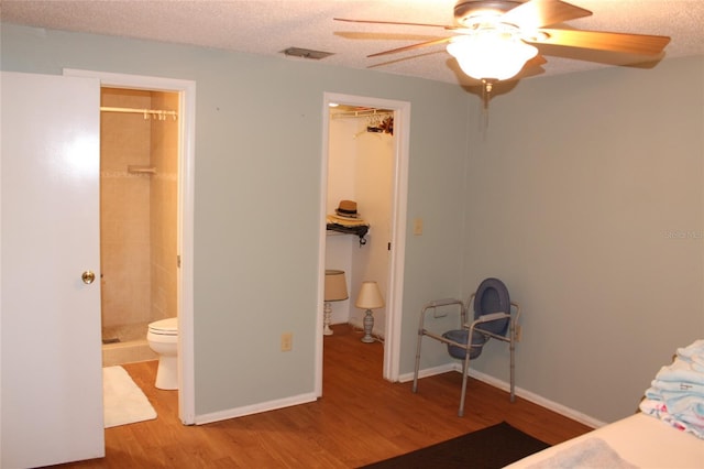 unfurnished bedroom featuring a spacious closet, wood finished floors, visible vents, and a textured ceiling