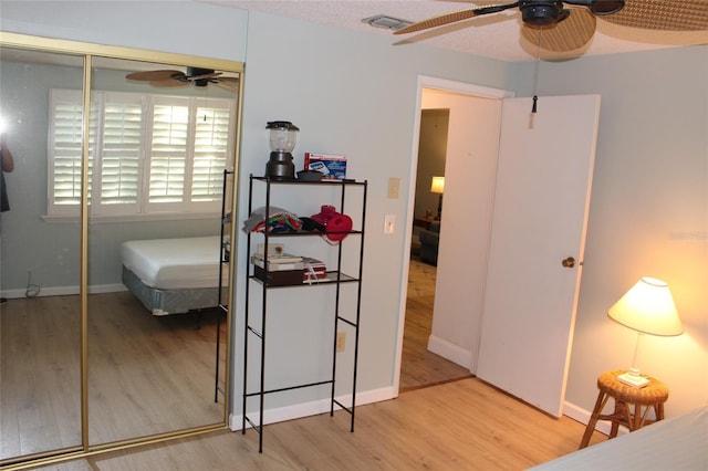 bedroom featuring wood finished floors, visible vents, baseboards, a closet, and a textured ceiling