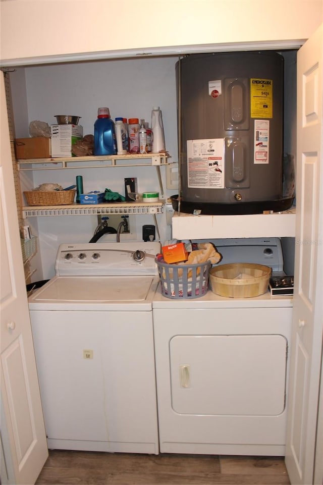 clothes washing area featuring washing machine and dryer, wood finished floors, water heater, and laundry area