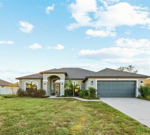 view of front facade featuring stucco siding, an attached garage, concrete driveway, and a front yard