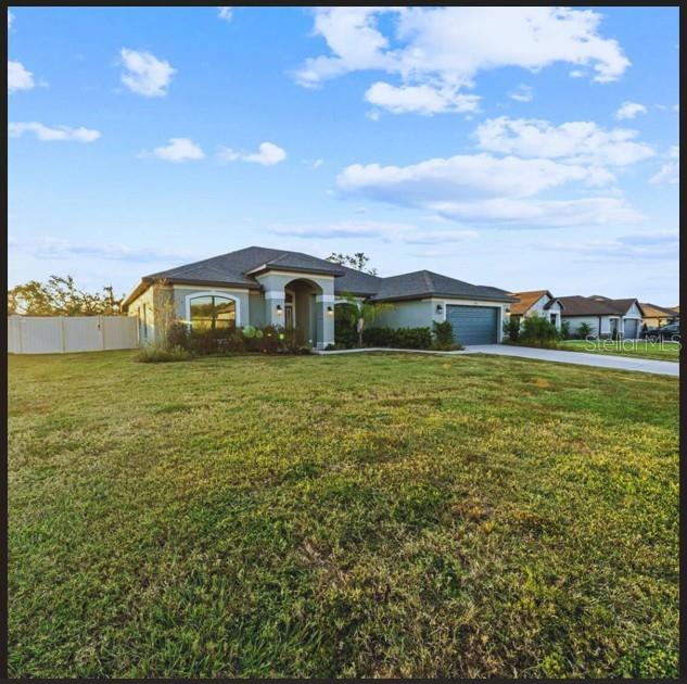 view of front of property with a front lawn, fence, a garage, and driveway