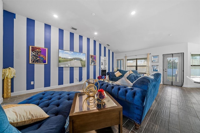 living area featuring visible vents, baseboards, wood finish floors, wallpapered walls, and vaulted ceiling