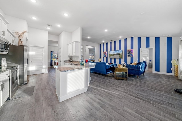 kitchen with dark wood-style floors, wallpapered walls, stainless steel appliances, white cabinets, and open floor plan