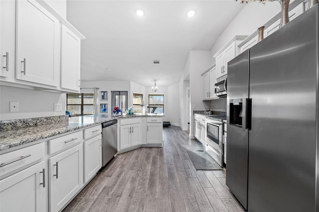 kitchen with light wood-style flooring, appliances with stainless steel finishes, a peninsula, and white cabinets