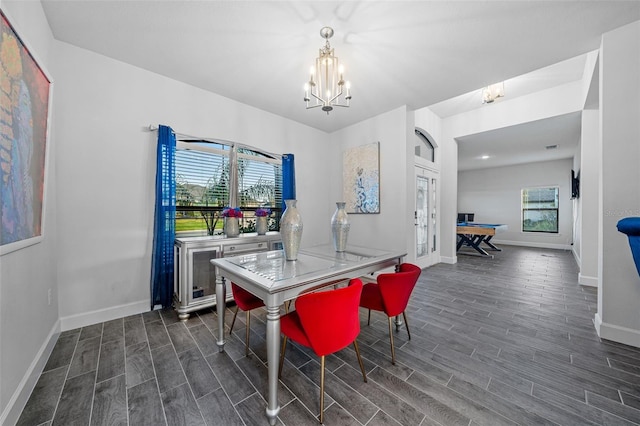 dining space featuring wood finish floors, baseboards, and a chandelier