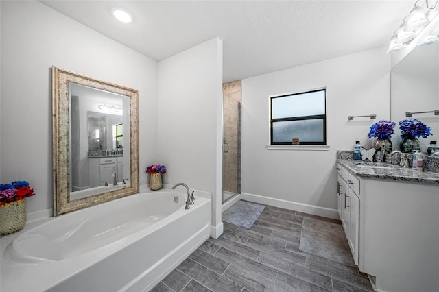 full bathroom with vanity, baseboards, wood finish floors, a shower stall, and a garden tub