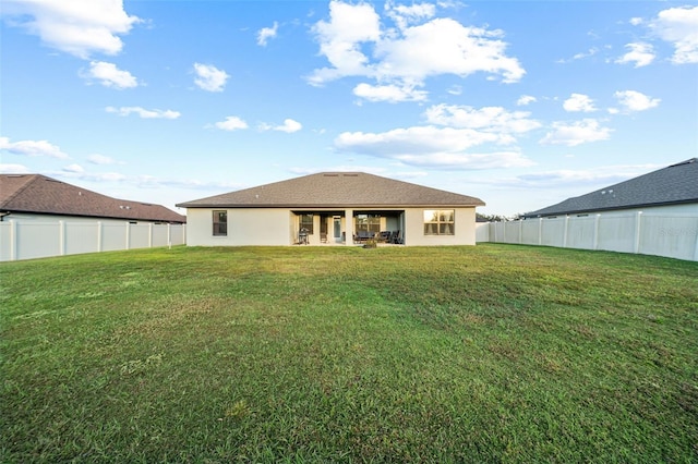 rear view of property with a lawn, a fenced backyard, and stucco siding