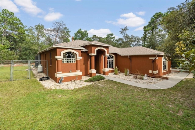 view of front of property featuring stucco siding, fence, a front lawn, and a gate