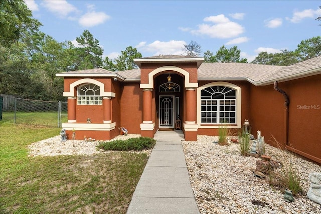 view of front of home with a front yard, fence, and stucco siding