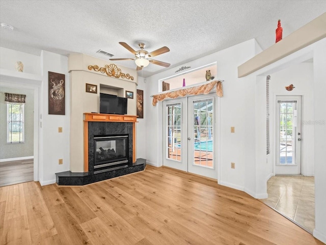 unfurnished living room featuring ceiling fan, visible vents, a textured ceiling, and wood finished floors