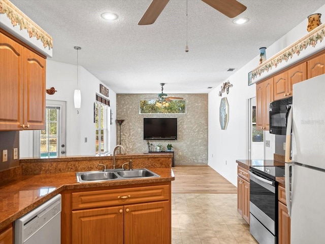 kitchen with white appliances, a ceiling fan, wallpapered walls, a peninsula, and a sink