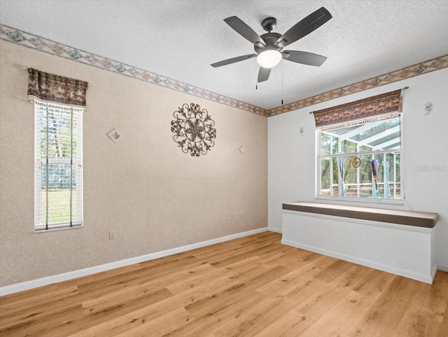 spare room featuring baseboards, a textured ceiling, ceiling fan, and light wood finished floors