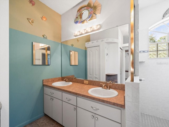 full bathroom with double vanity, tile patterned floors, and a sink